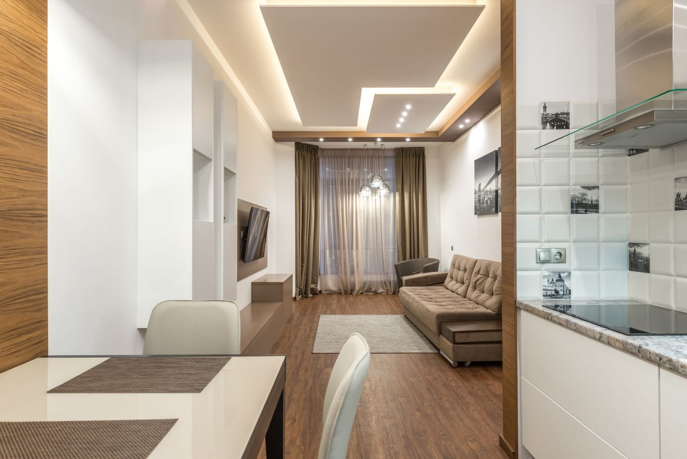 A finished apartment with a lit false ceiling, wooden panelling and a dining area