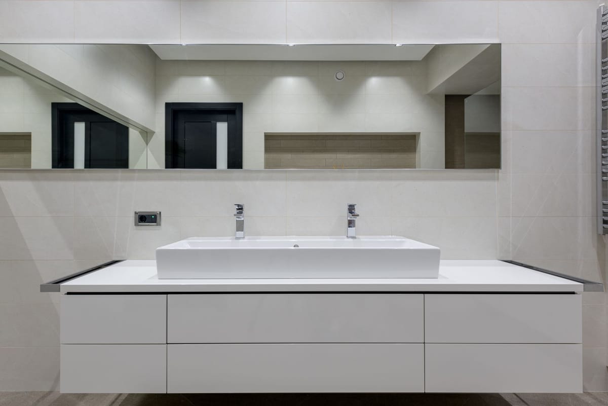 A bathroom with a floating white vanity and wide mirror