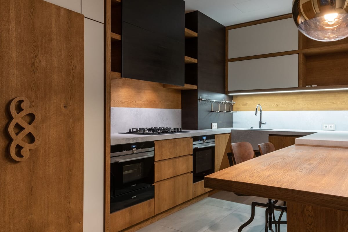 A modern wooden kitchen with built-in oven and hob