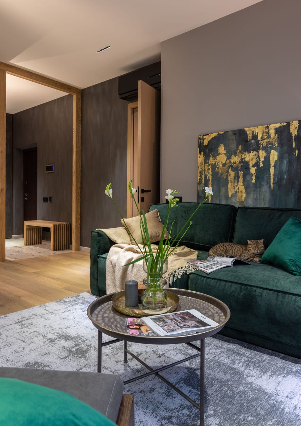 A living room with a deep green sofa, coffee table and warm wall panelling
